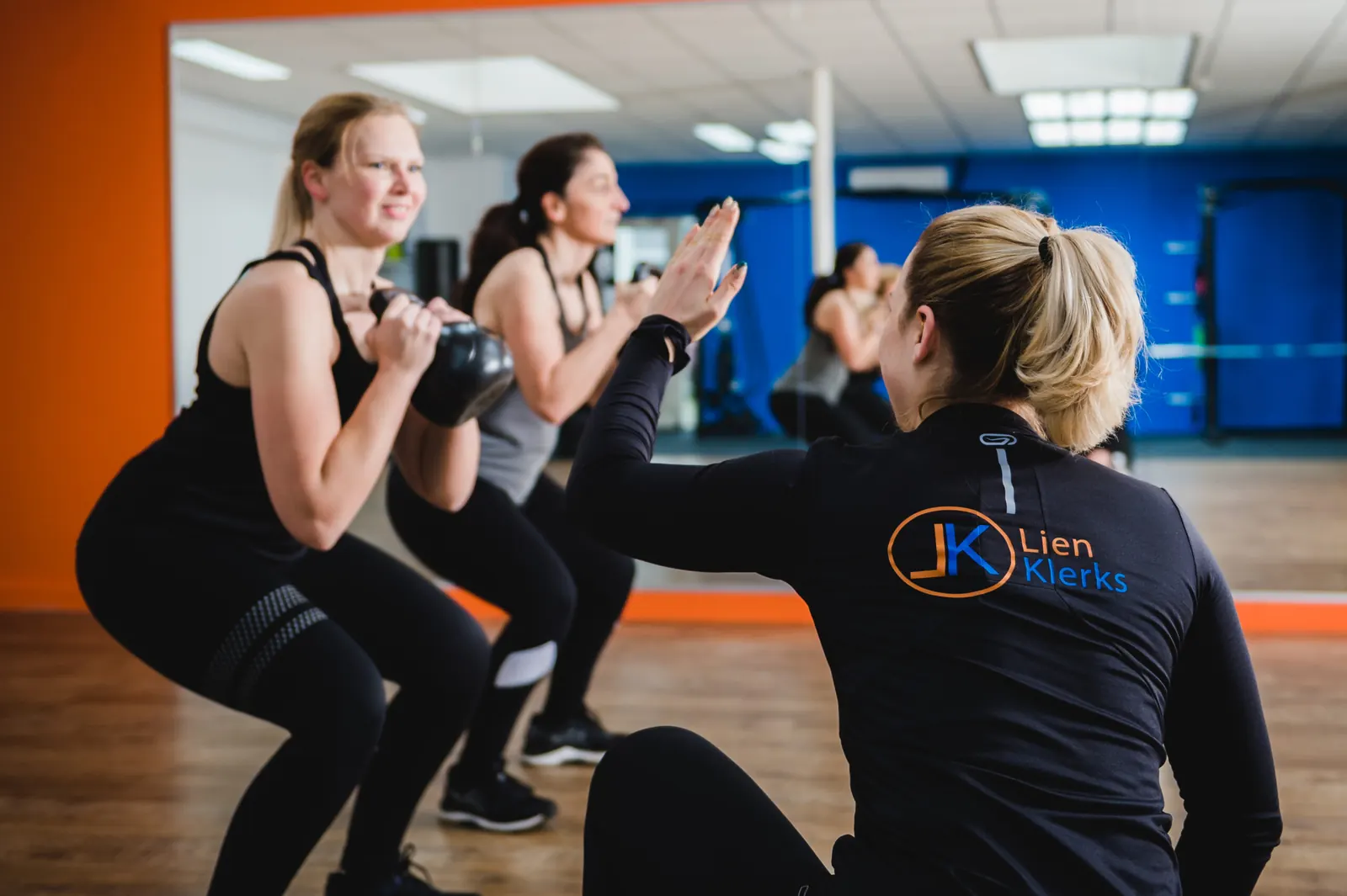 Lien begeleidt een deelnemer bij een squat